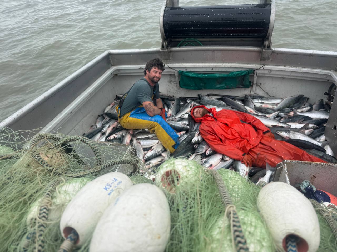 Hard-working crew resting on a deck of salmon